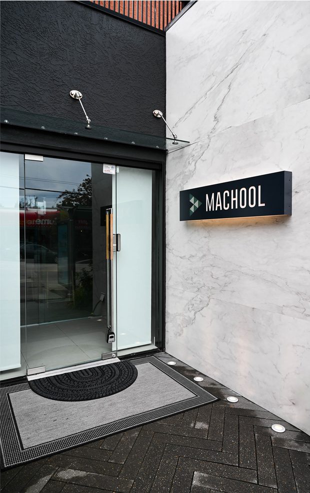 Entrée sur rue avec l'enseigne Machool fixée sur un mur de marbre
