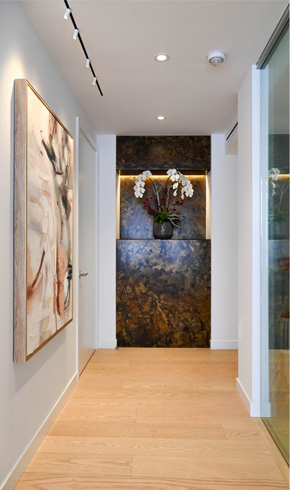 Couloir bordé d'œuvres d'art et alcôve éclairée garnie d'orchidées