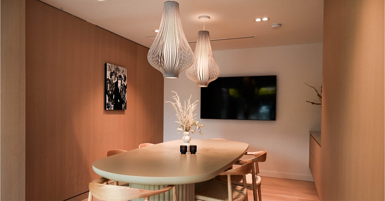 Salle de réunion avec table ovale, suspensions tressées et écran mural